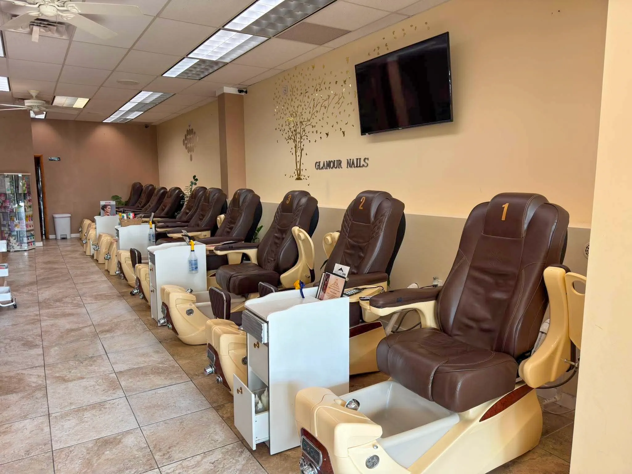 Glamour Nails salon interior in Blasdell, NY — row of brown spa pedicure chairs beneath the Glamour Nails wall art